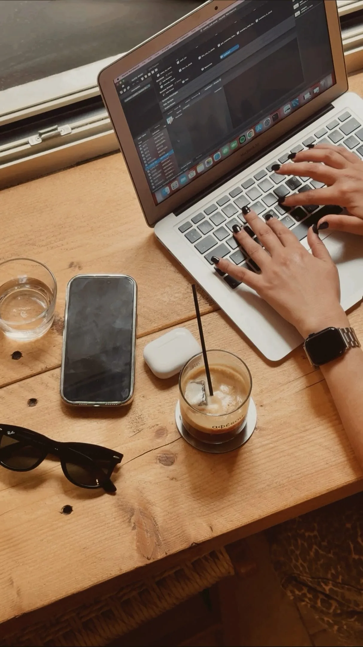 Δουλειά το πρωί με laptop και iced coffee afésou πάνω σε ξύλινο τραπέζι